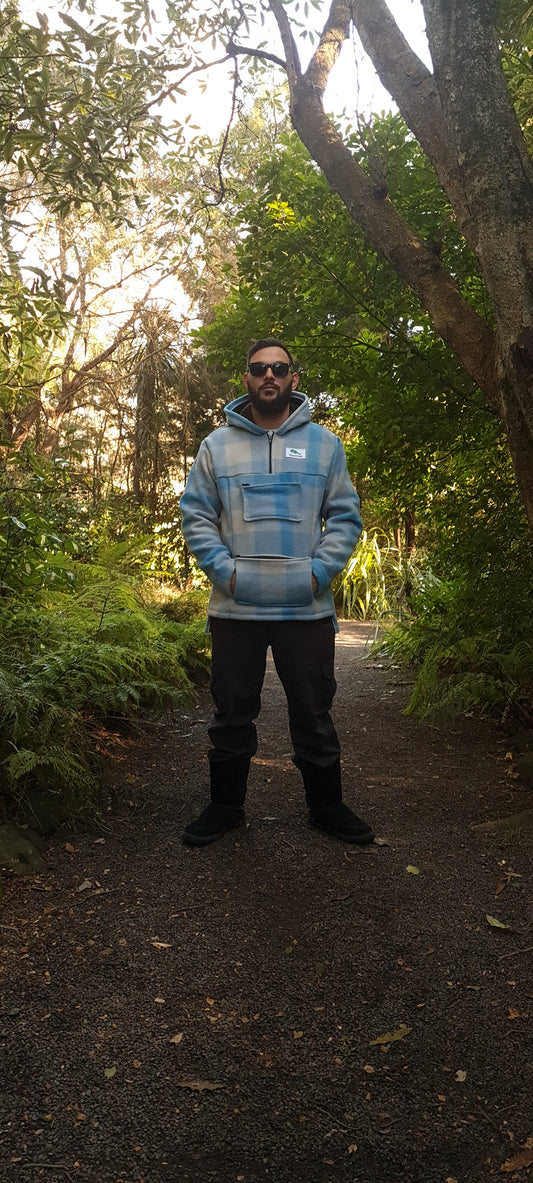 Experience the allure of Maori-inspired fashion in the Checked Light Blue Raumoa Wool Anorak Jacket, a wool jacket that seamlessly blends style and tradition for a unique and trendy look. front picture.