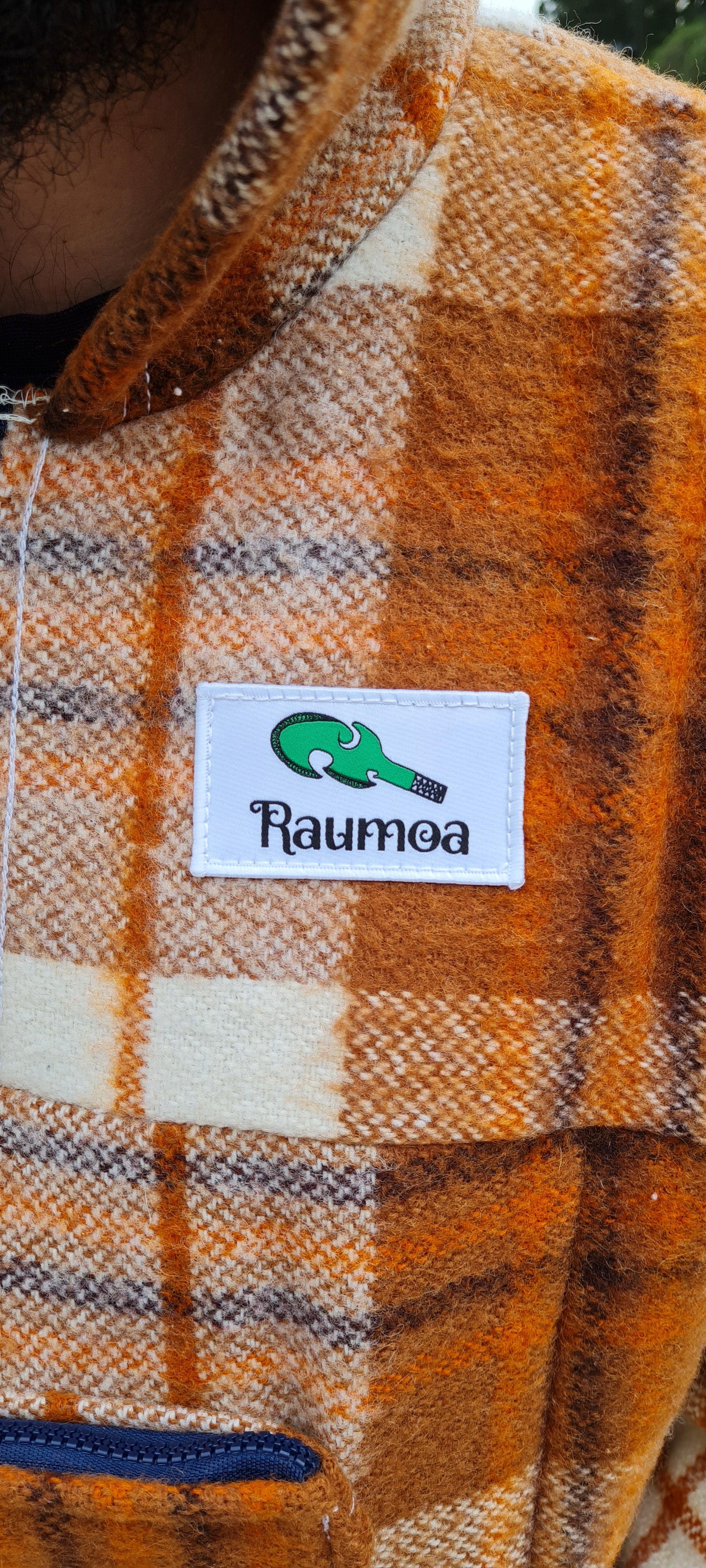 Experience the artistry of Maori-inspired design in the Checked Brown Raumoa Wool Anorak Jacket, a wool coat that embodies the fusion of heritage and contemporary woolen fashion. logo picture